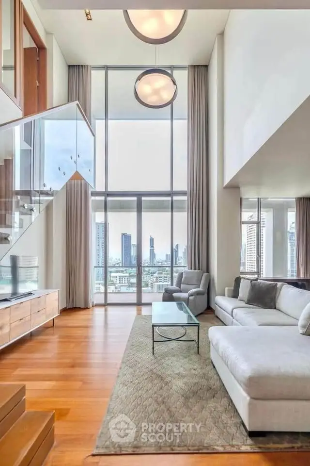 Luxurious modern living room with high ceilings and city view, featuring elegant furniture and large windows.