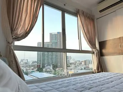 Bright bedroom with large window offering stunning city view, elegant curtains, and cozy bedding.
