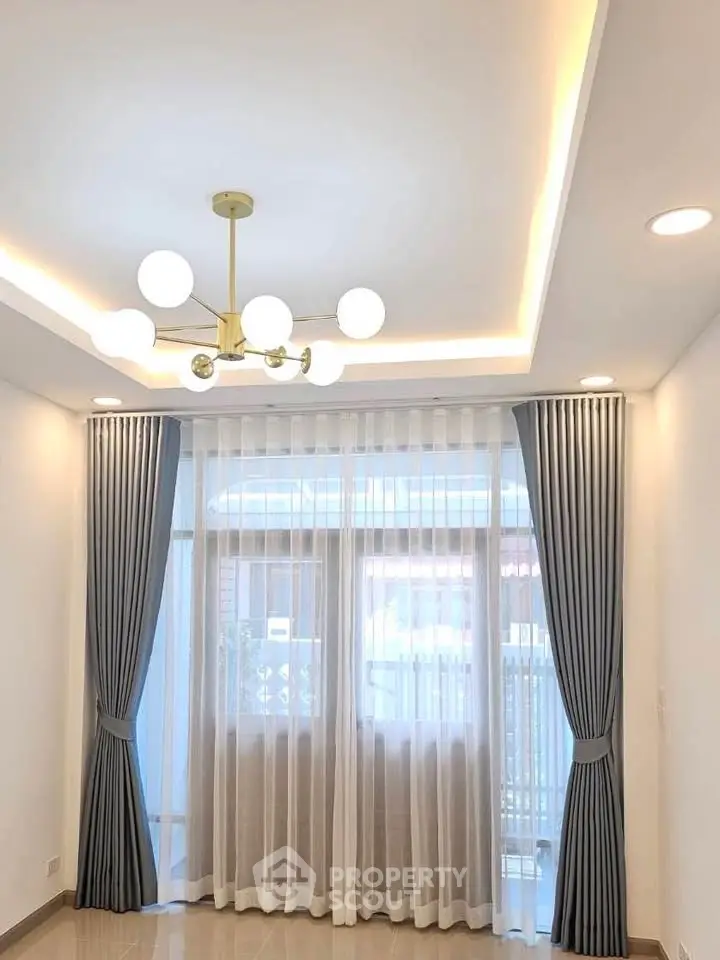 Elegant living room with modern chandelier and floor-to-ceiling windows.