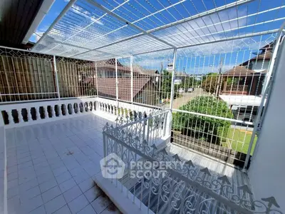 Spacious tiled balcony with decorative railing and clear sky view in suburban home.