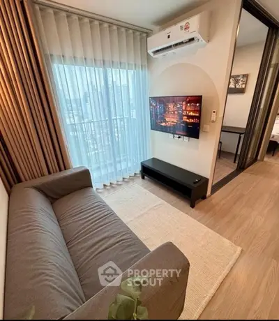 Modern living room with city view, featuring a sleek sofa and wall-mounted TV.