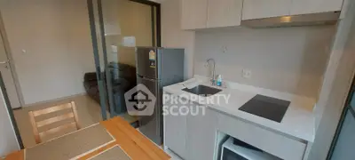Modern kitchen with sleek cabinetry and dining area in contemporary apartment.