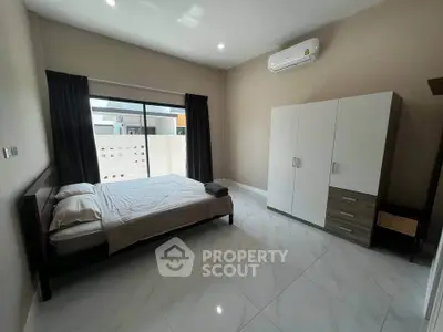 Spacious modern bedroom with large window and sleek furnishings in a contemporary home.