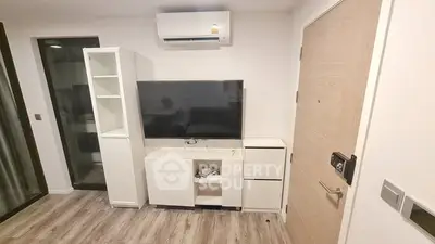 Modern minimalist living room with sleek white entertainment unit, large flat-screen TV, and wood laminate flooring, perfect for cozy urban living.