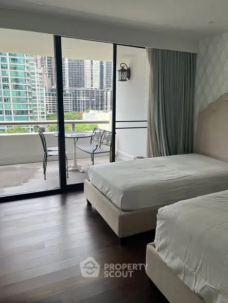 Luxurious bedroom with balcony offering stunning city views and elegant furnishings.