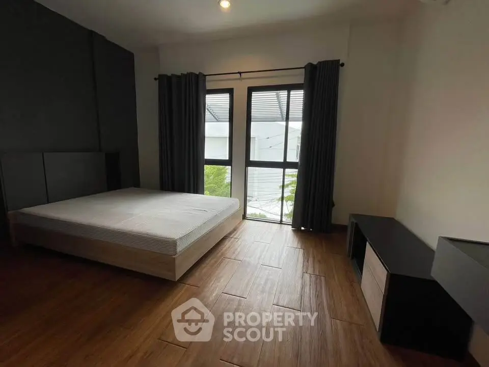 Spacious bedroom with large window and modern furnishings, perfect for comfort and relaxation.