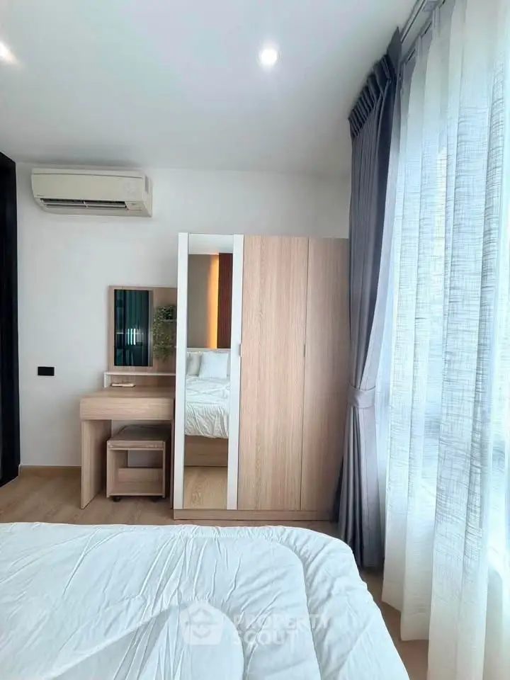 Modern bedroom with sleek furniture and large window for natural light.