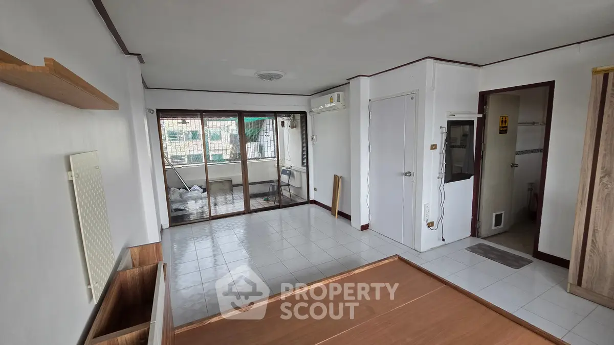 Spacious unfurnished living room with large windows and balcony access.