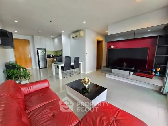 Modern living room with red sofa, sleek TV unit, and dining area in open layout.