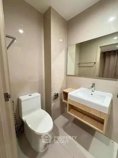 Modern bathroom with sleek fixtures and neutral tones, featuring a spacious mirror and elegant sink design.