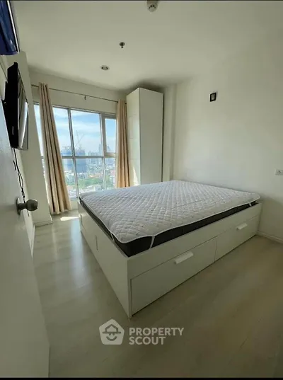 Bright bedroom with city view, featuring a modern bed with storage and wall-mounted TV.
