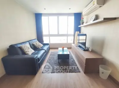 Modern living room with large window, leather sofa, and sleek TV setup.
