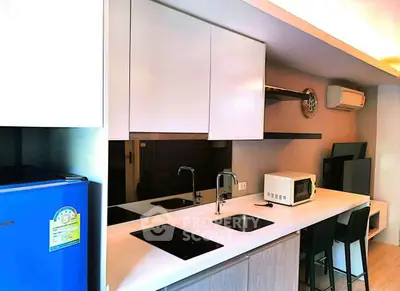 Modern kitchen with sleek design, featuring a microwave, induction cooktop, and compact refrigerator.