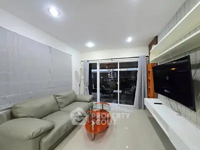 Modern living room with sleek furniture and large TV, perfect for relaxation.