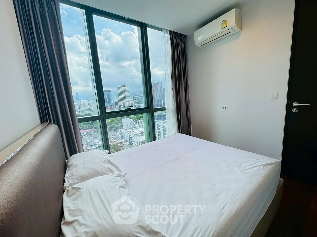 Modern bedroom with city view and large windows in a high-rise apartment.