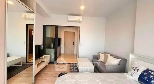 Modern studio apartment with sleek design and cozy furnishings, featuring a mirrored wardrobe and compact living area.