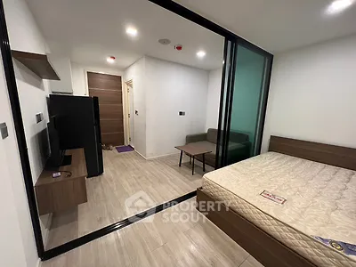 Modern studio apartment with glass partition, featuring a cozy living area and sleek wooden flooring.