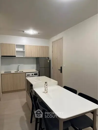 Modern kitchen with dining area in a sleek apartment, featuring wooden cabinetry and stainless steel appliances.
