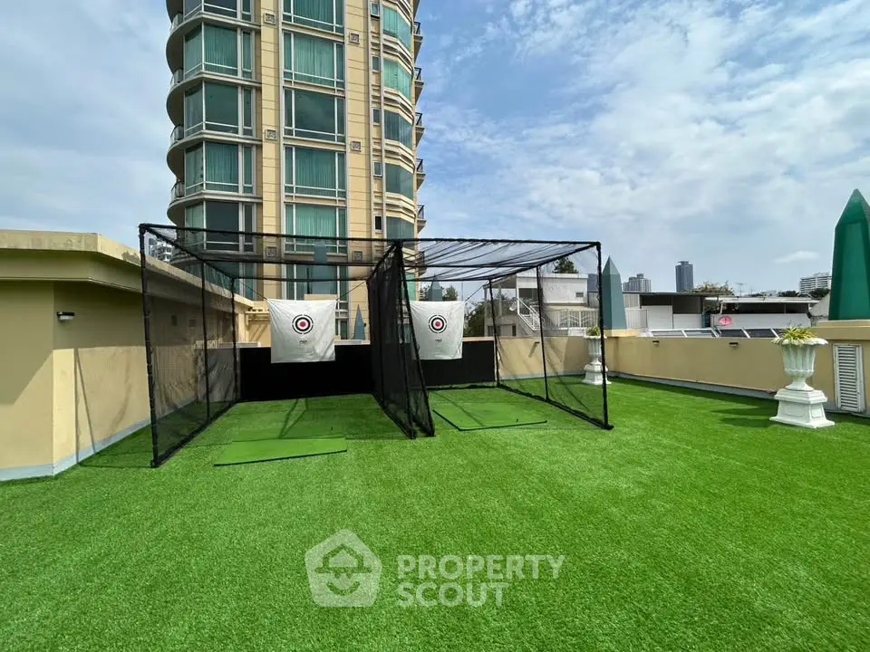 Rooftop golf practice area with city view and modern building backdrop.