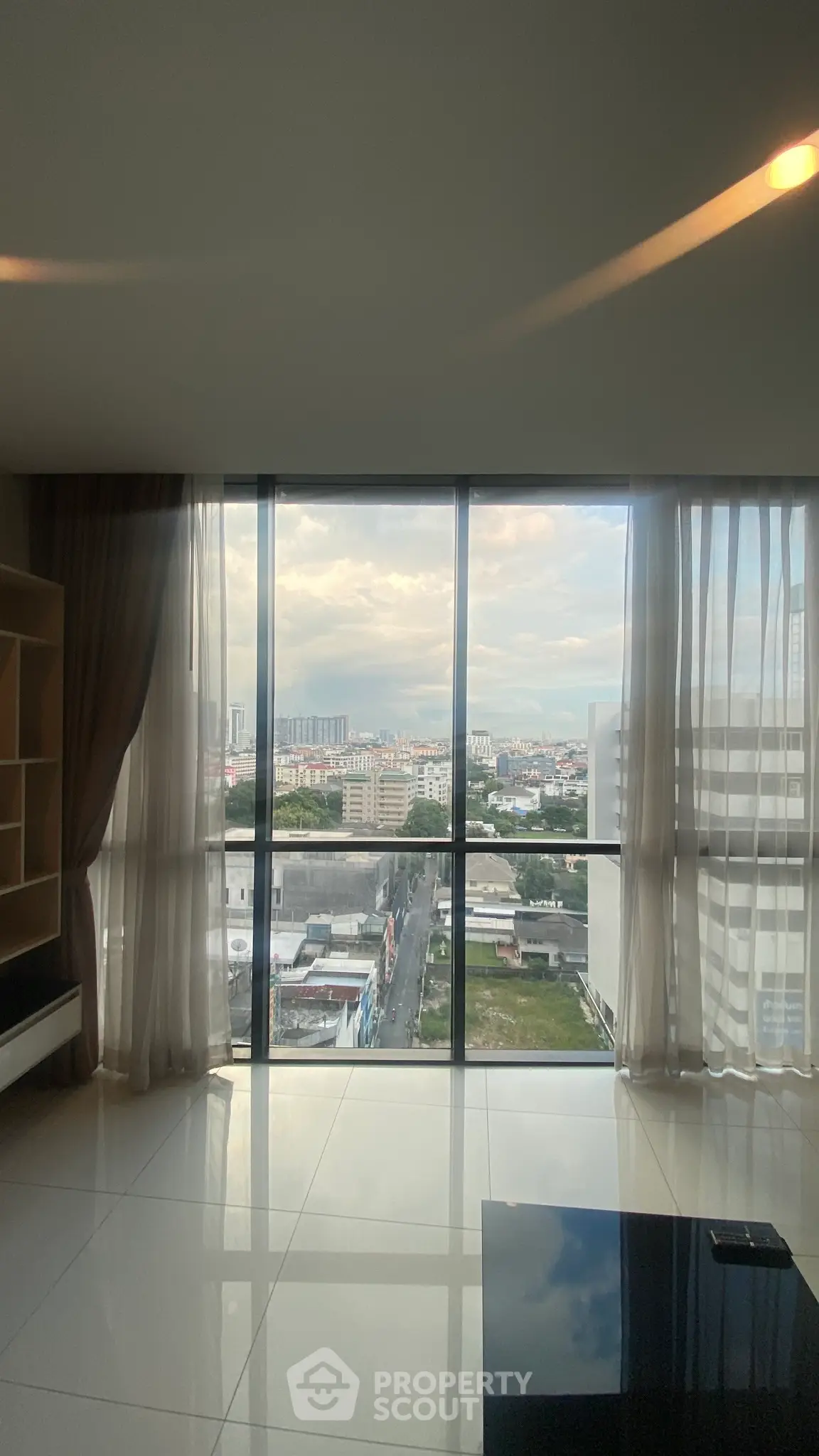 Spacious living room with floor-to-ceiling windows offering stunning city views.