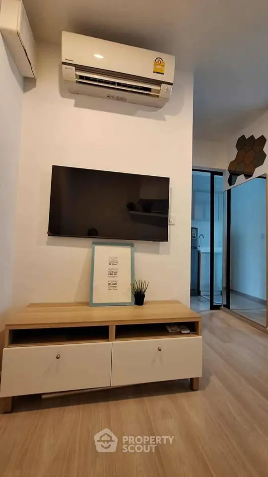 Modern living room with wall-mounted TV and air conditioning in stylish apartment.