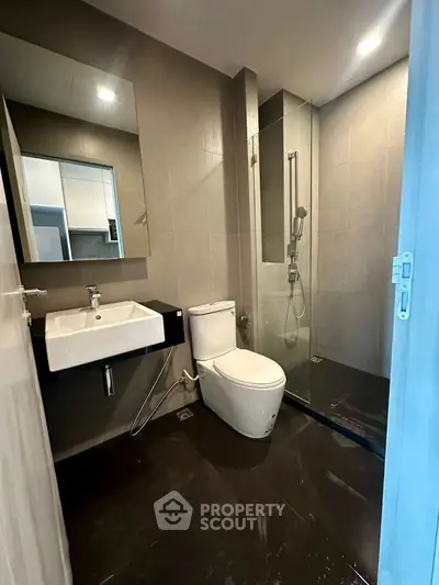 Modern bathroom with sleek fixtures and glass shower enclosure in contemporary apartment.