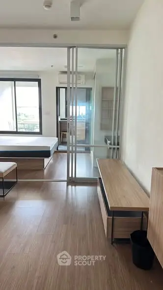Modern apartment interior with sliding glass doors and wooden flooring, featuring a spacious layout and natural light.