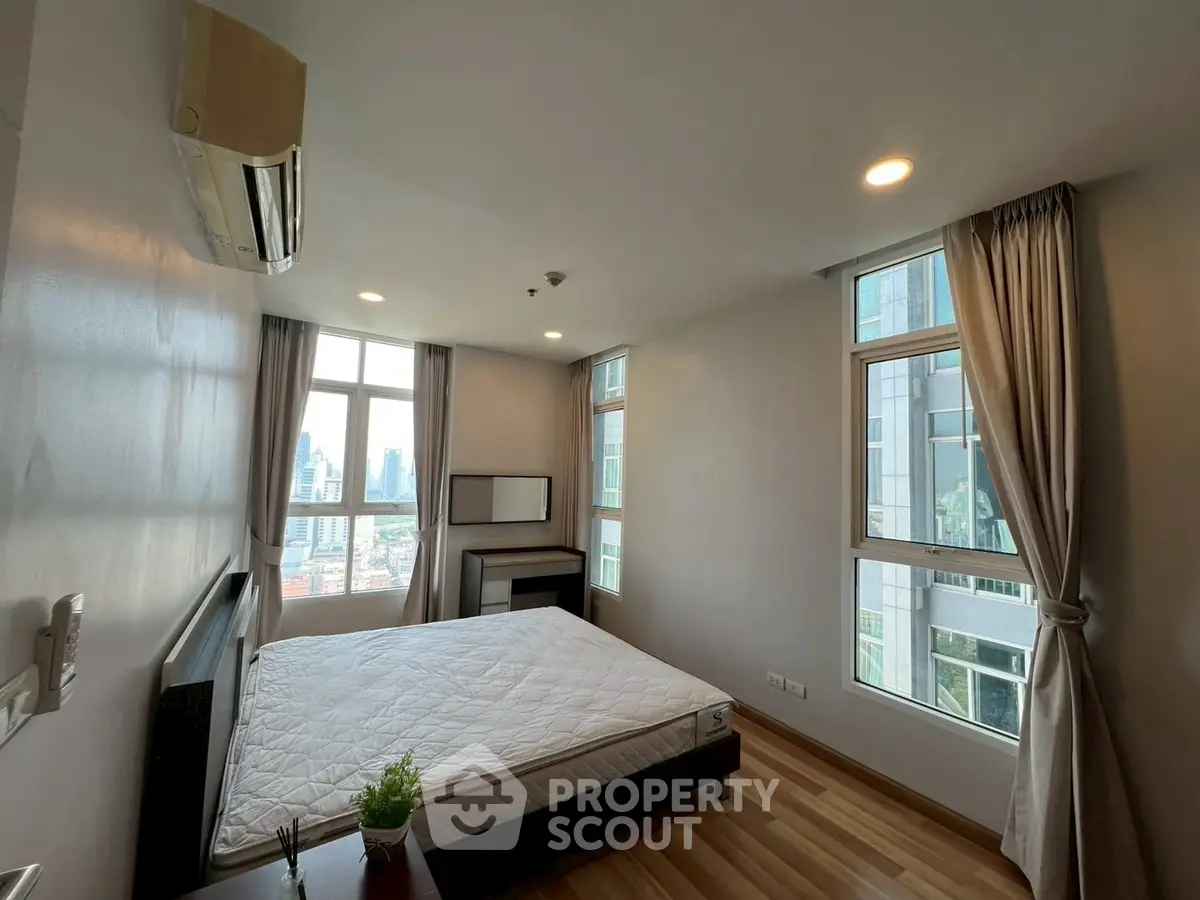 Spacious bedroom with city view and modern decor in high-rise apartment