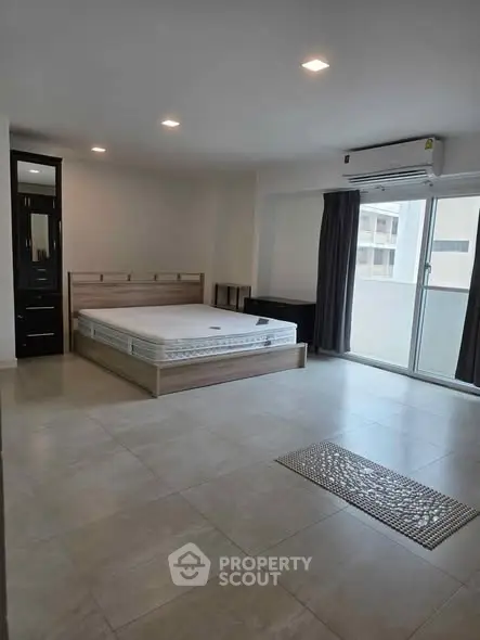 Spacious modern bedroom with large windows and sleek tile flooring.