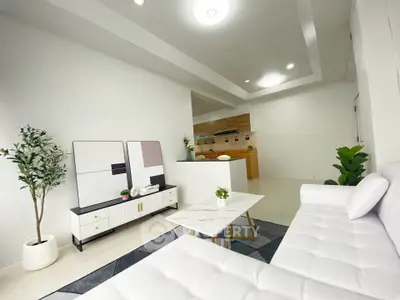 Modern living room with sleek white furniture and open kitchen layout