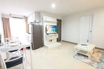 Modern living room with dining area and TV, featuring sleek furniture and bright natural lighting.