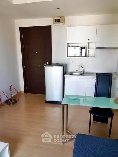 Modern compact kitchen with sleek appliances and stylish dining area in a cozy apartment.