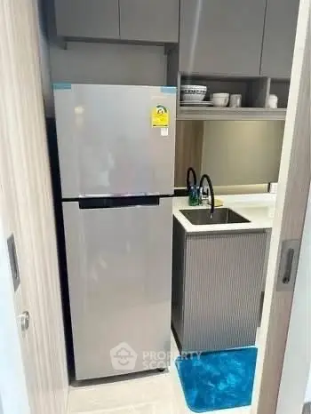 Compact modern kitchen with sleek fridge and sink in a cozy apartment.