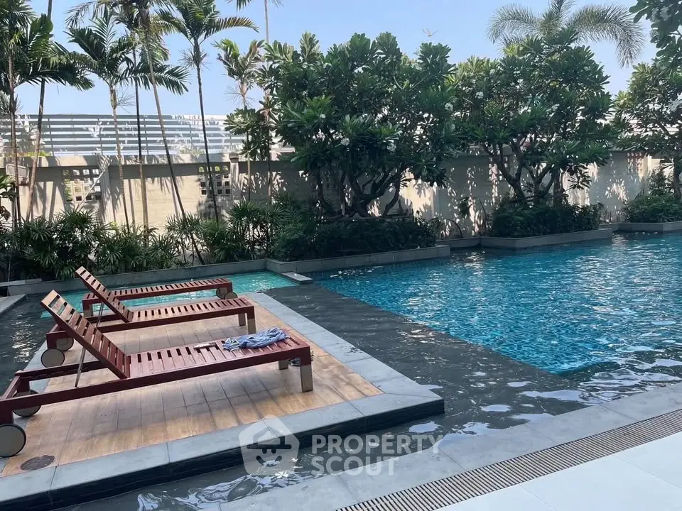 Luxurious outdoor pool area with sun loungers and lush greenery, perfect for relaxation and leisure.