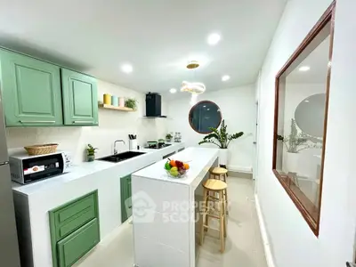 Modern kitchen with green cabinets, sleek white countertops, and stylish lighting.