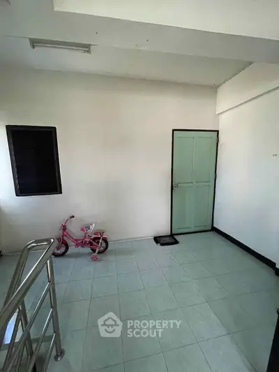 Spacious interior with tiled flooring and a mint green door, perfect for versatile use.