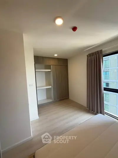 Modern bedroom with large window and built-in wardrobe in a stylish apartment.