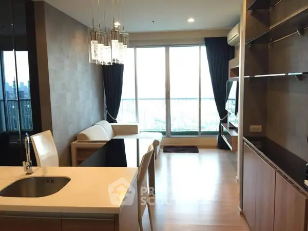 Modern living room with open kitchen and city view, featuring elegant lighting and sleek furnishings.