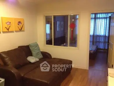 Cozy living room with brown leather sofa and wooden flooring, perfect for relaxation.
