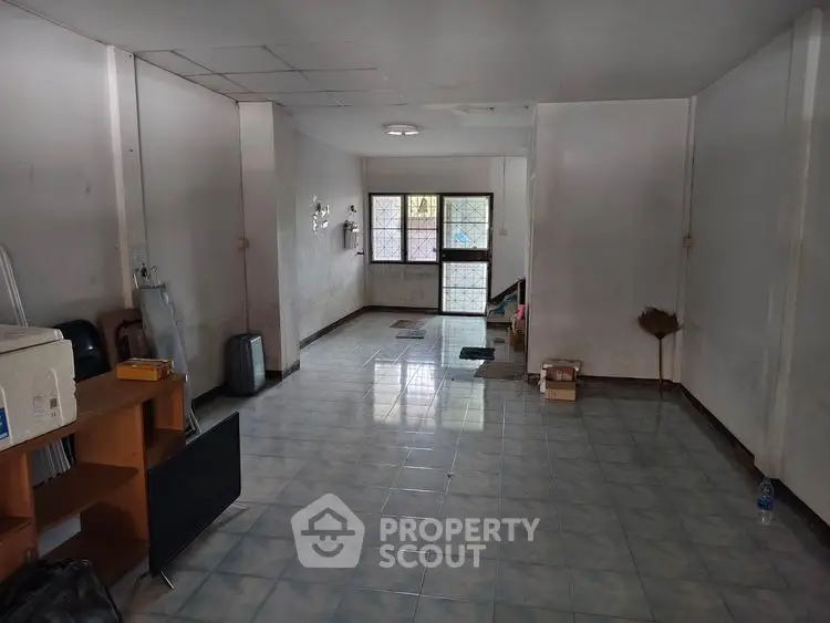 Spacious unfurnished room with tiled flooring and large window, ideal for customization.