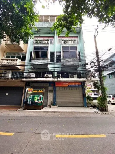Street view of commercial building with closed shops and residential units above.
