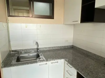 Modern kitchen with granite countertops and sleek cabinetry in a contemporary apartment.