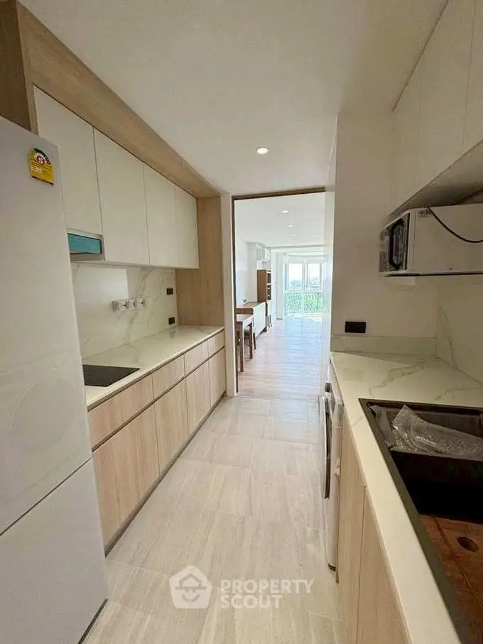 Modern kitchen with sleek cabinetry and open layout leading to dining area