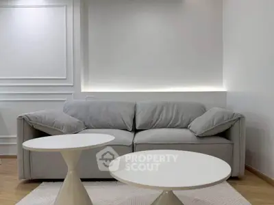 Modern living room with stylish gray sofa and chic white tables