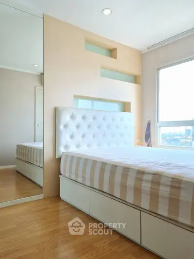 Modern bedroom with stylish headboard and large window offering city views.
