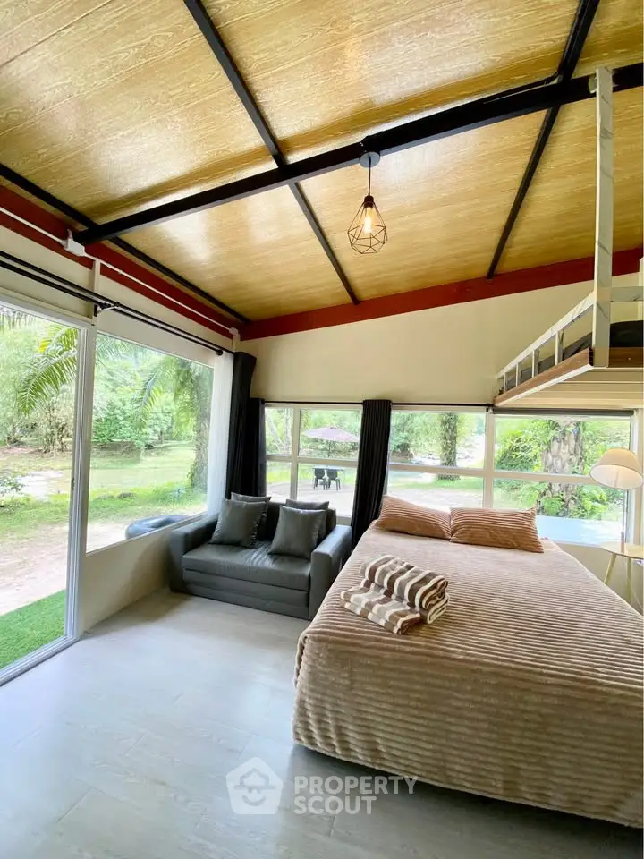 Charming bedroom with large windows and garden view, featuring a cozy bed and stylish decor.