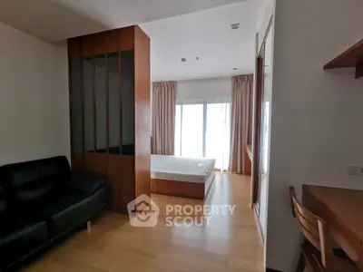 Spacious modern bedroom with wooden flooring and large windows for natural light.