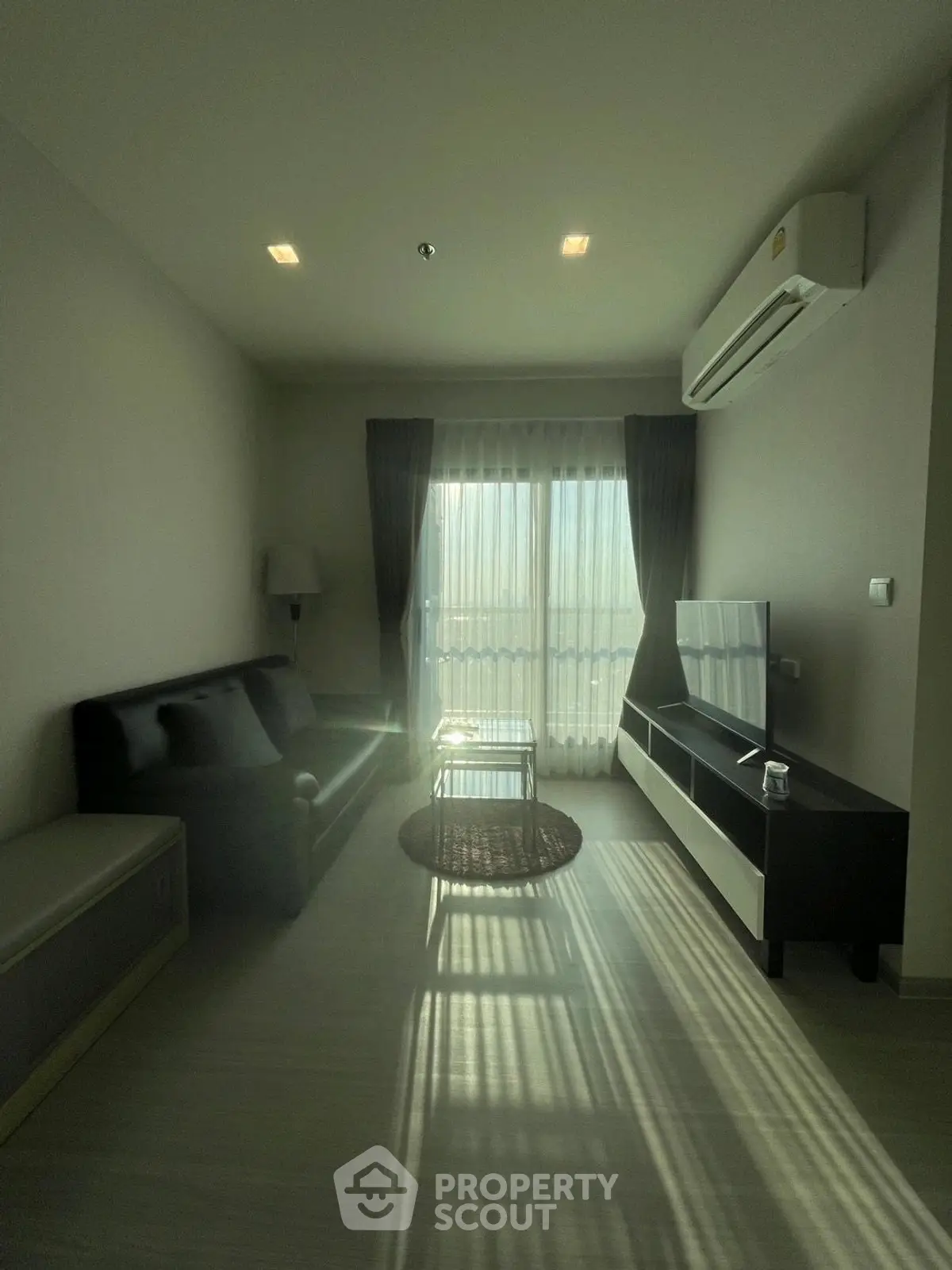 Modern living room with sleek furniture and natural light from large window.