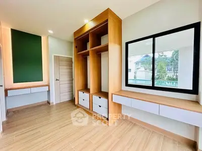 Spacious modern room with built-in wooden storage and large window view.