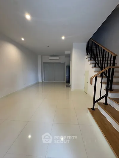 Spacious modern living room with sleek staircase and air conditioning